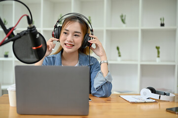 Attractive Asian female radio host or podcaster running her podcast channel in studio.