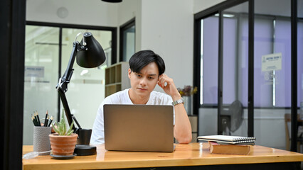 Handsome Asian male office employee or college student, confused with his assignment