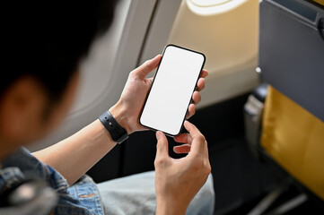 Male passenger using his smartphone during the flight. phone white screen mockup.