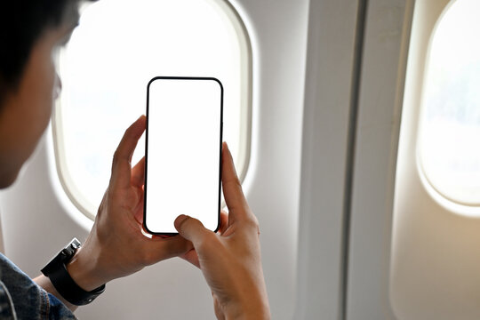Male passenger using his smartphone to taking a picture during the flight. phone white screen mockup