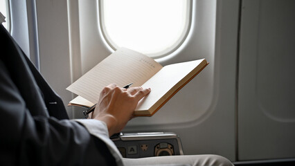 Successful Asian businessman reading a book during the flight for his business trip.