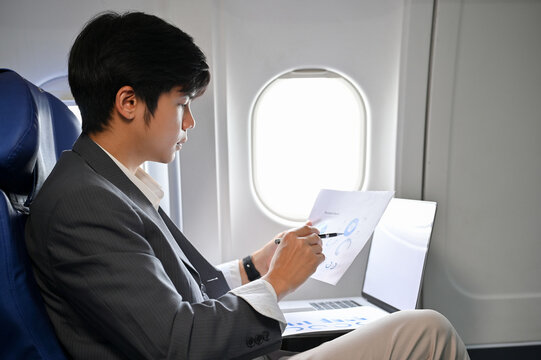 Professional Asian businessman concentrating analyzing a financial data during the flight