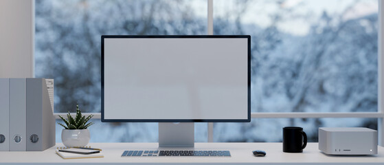 Modern office desk with computer mockup, supplies and decor over the window with snow view.