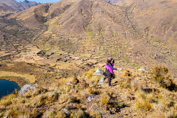 Latin woman looking at the cell phone on top of an Andean mountain