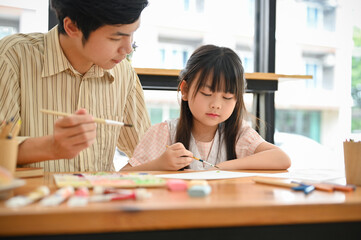 A cute Asian girl is concentrating painting picture with a watercolor, learning art