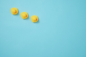 水色背景に一列に並ぶ黄色いアヒルの置物