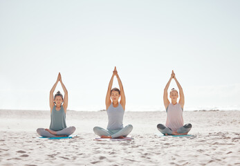 Zen, meditation and yoga at the beach with women for wellness, fitness and health. Stretching, lotus pose and friends doing a pilates workout or exercise for mobility, flexibility or mindfulness.
