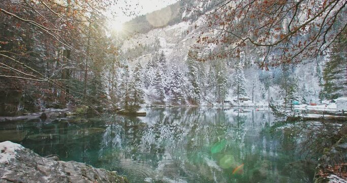 Scenic view of famous mountain lake Blausee located in the Kander valley above Kandergrund in the Jungfrau region, Switzerland. Romantic blue lake nature park in the Bernese Alps during winter season.