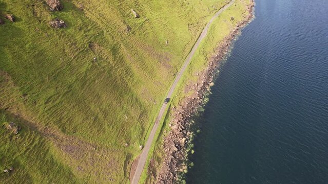 Aerial view of a car driving along the coastline on Isle of Mull, Scotland, United Kingdom.