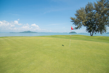 Fototapeta na wymiar Green golf of golf course blue sky and red flag
