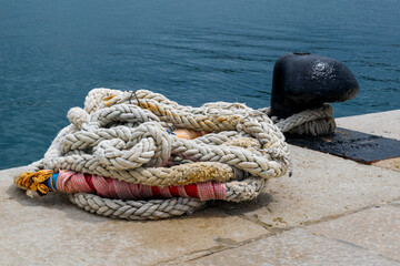Fototapeta na wymiar Multicolored nautical rope piled next to a mooring bollard