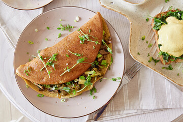 Vegan pancakes filled with mushrooms, pea sprouts, avocado. Eggs benedict with plant-based sauce, sourdough bread, tofu, young onion, greens. Healthy breakfast
