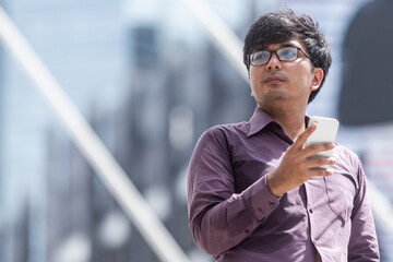  Asian business man purple with tshirt  looking up at skyscrapers while walking in the street in downtown of modern city