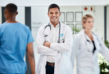 Happy, medical and doctor in hospital with smile and confident, arms crossed in busy hallway. Male,...