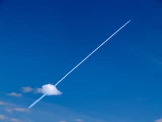 Fototapeta premium Small jets in distance create diagonal chem-trails across blue sky through small puffy lower cloud.