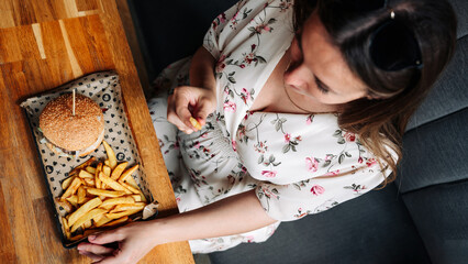 Pregnant woman hamburger eat. Hungry pretty pregnancy female eating tasty burger. Fast food, people and unhealthy eating concept.