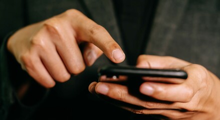 Close-up businessman holding a mobile phone, checking information and communicating.