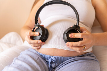 Pregnancy therapy music. Pregnant woman listening to music. Mother belly listen headphones sound. Pregnancy, medicine health care and people concept.