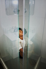 Fototapeta na wymiar Depression, anxiety and stress girl thinking in a shower at home. Black woman suffering from mental health, anxiety and depressed after relationship, personal problem or life crisis in house bathroom
