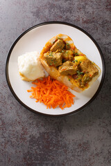 South African Bunny Chow bread stuffed with lamb curry with vegetables close-up on a plate on the table. vertical top view from above