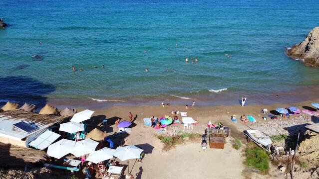 Hippie nudist area with beach party bar.
Calm aerial view flight boom slider drone of Aigües Blanques beach Ibiza summer day july 2022. Marnitz 4k Cinematic from above