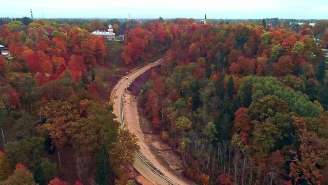 Aerial drone shot over forest in Gauja National Park leading upto Sigulda Castle on a cloudy day in Latvia at daytime.