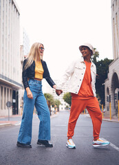 Happy interracial couple with fashion clothing in a urban city street with a smile and love. Trendy, stylish or punk man and woman walking in a town road with funky, edgy and style together