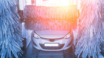 Car washing automatic carwash. Brush washer clean blue auto car on automatic car wash station....