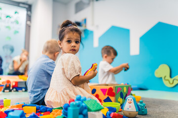 Playtime at nursery school. Toddlers sitting on the floor and playing with building blocks,...