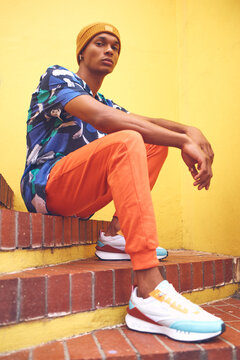 Black man, fashion and street style clothes on cool, trend or attitude model on steps by city wall background on building. Portrait of serious student sitting on stairs in urban punk clothing outdoor