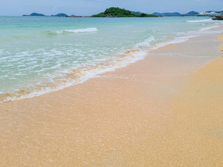 Soft moving sea waves foams in wet sandy beach. Beautiful golden texture of sea water and sand.