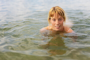 Fototapeta na wymiar eautiful woman swimming in the ocean. Smiling blonde girl enjoy in sunny day.
