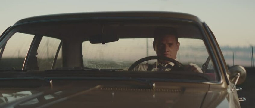 Smiling man sitting in classic car. Retro style detective using deduction for solving challenging cases.