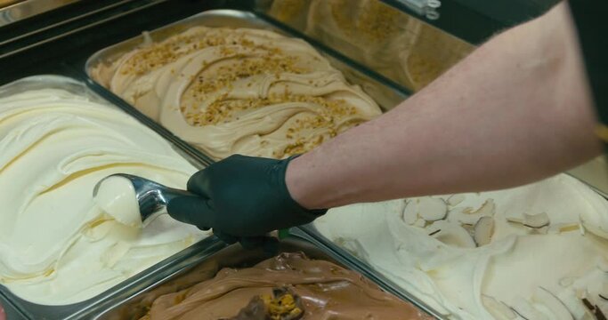 Scooping a gelato ice cream from a showcase in ice cream shop