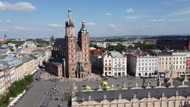 Steeple and clock tower at St. Mary's Basilica - City Centre flyover of Krakow, Poland, a Polish cultural capital, with medieval and renaissance architecture - 4K 30FPS Smooth Tracking Forwards