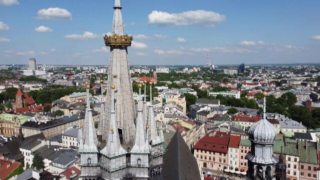 Steeple and clock tower at St. Mary's Basilica (Bazylika Mariacka)- City Centre flyover of Krakow, Poland, a Polish cultural capital with medieval and renaissance architecture - 4K 30FPS Tracking Down