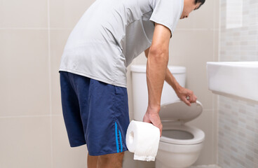 Man standing in bathroom holding tissues with severe stomach pain. stomach cramps, Abdominal pain,...
