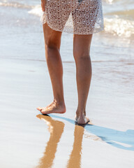 Feet of a girl walking along the sandy seashore.