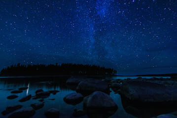 Astrophotography of landscape with a beautiful night starry sky and Milky way over water of sea...