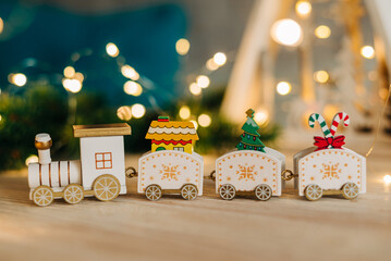 Close up of train toy decoration with with Christmas tree garland lights flickering in background. shallow depth of field. xmas gift card concept.