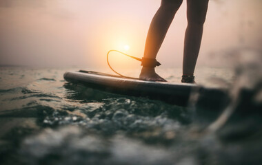 Low angle view of woman legs balancing on paddle board 
