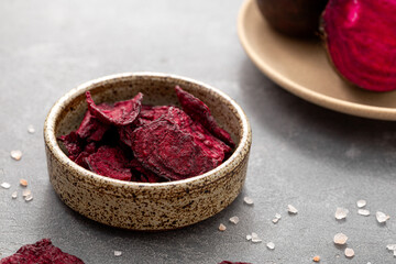 Obraz na płótnie Canvas Beetroot chips in a bowl on a gray background. Healthy vegetable chips, snack for vegetarians