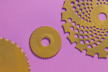Golden circular saw blades and a garden trimmer disc on a lilac background