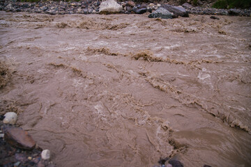 Muddy river water. Spring flood. Dirty muddy water with a whirlpool and white foam close-up.A mountain river or stream raging during a flash flood.