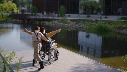 Disabled asian father having fun with his son near lake. Rehabilitation. Happy family fun spending time together. Father's day.