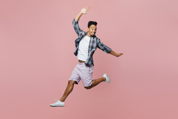 Fototapeta na wymiar Full body young man of African American ethnicity he wear blue shirt look camera jump high like flying with outstretched hands isolated on plain pastel light pink background. People lifestyle concept.