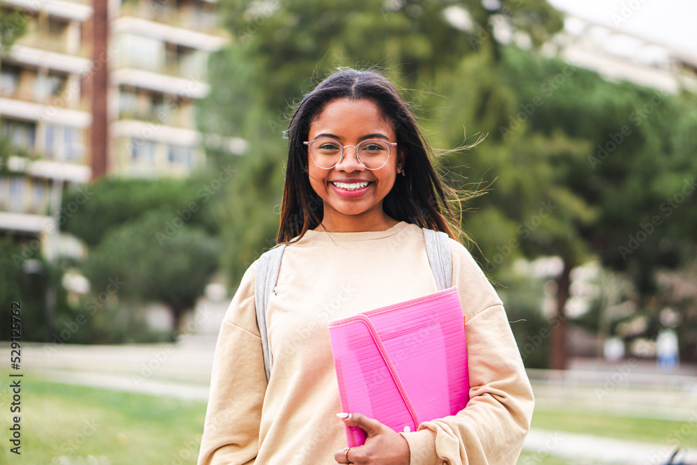 Wall mural happy hispanic school girl with glasses smiling and laughing out of class. cute teenage student stan