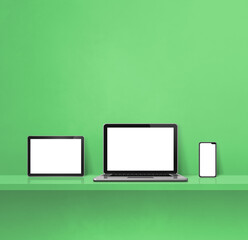 Laptop, mobile phone and digital tablet pc on green wall shelf. Square background