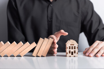 hand stops falling wooden dominoes falling on house model, real estate protection, home insurance, risk insurance concept, domino principle - obrazy, fototapety, plakaty