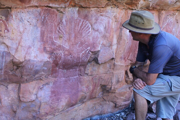 Australian man looking at Australian Aboriginal mythology rock paintings in Kimberley Western...